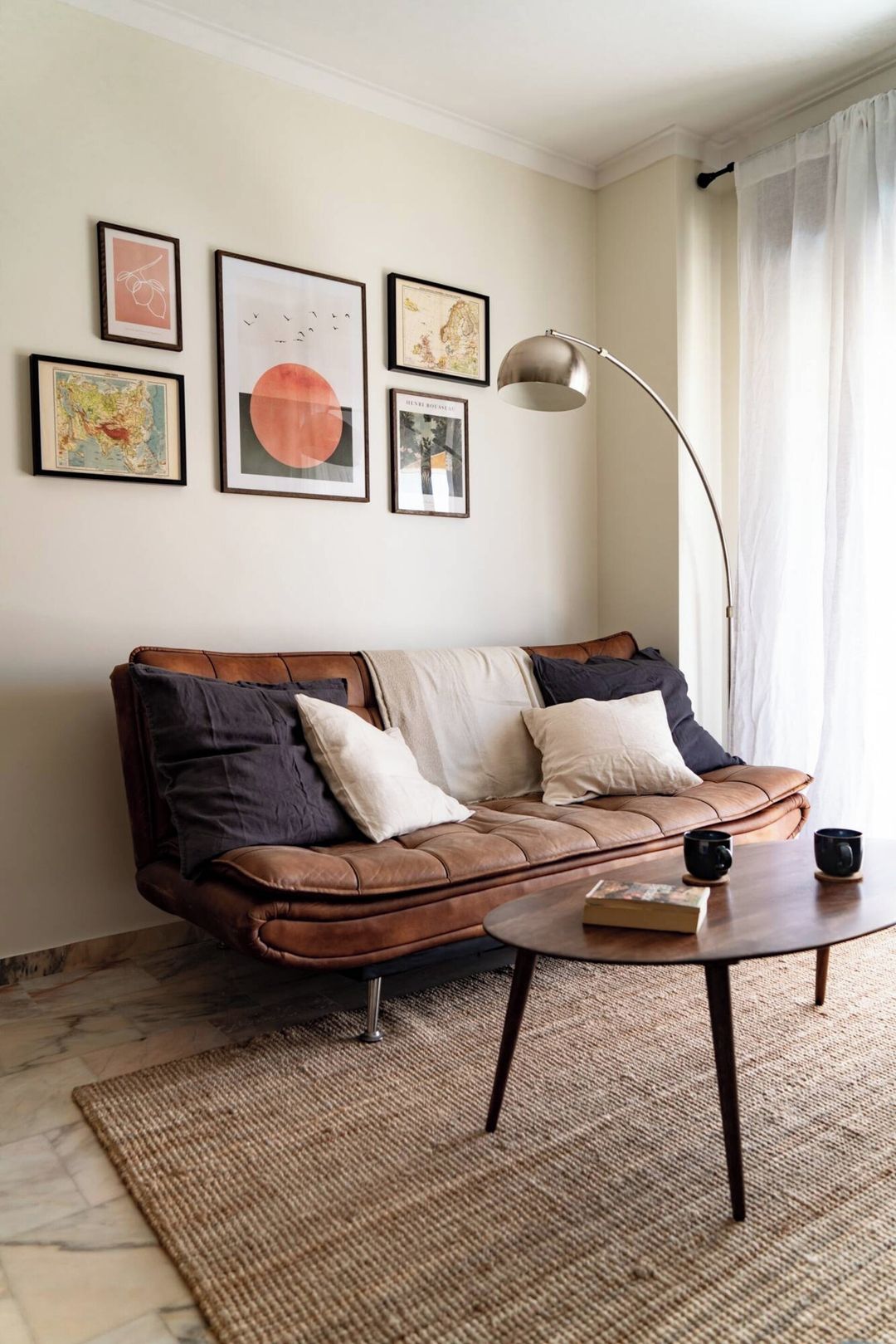 A living room with a brown leather sofa, a round coffee table, and a floor lamp.