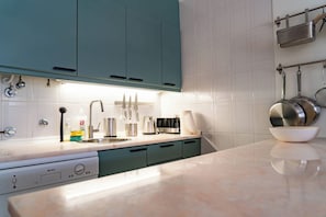 A modern kitchen with teal cabinets, a stainless steel sink, and a coffee maker.