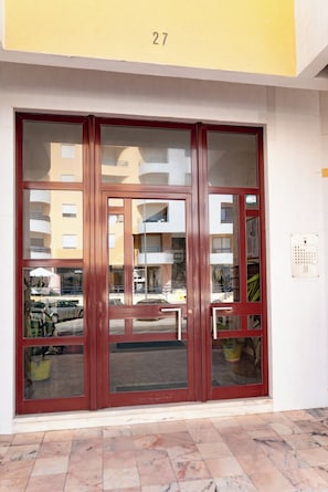 A set of glass doors with a metal handle, a number '27' above, and a tiled floor.