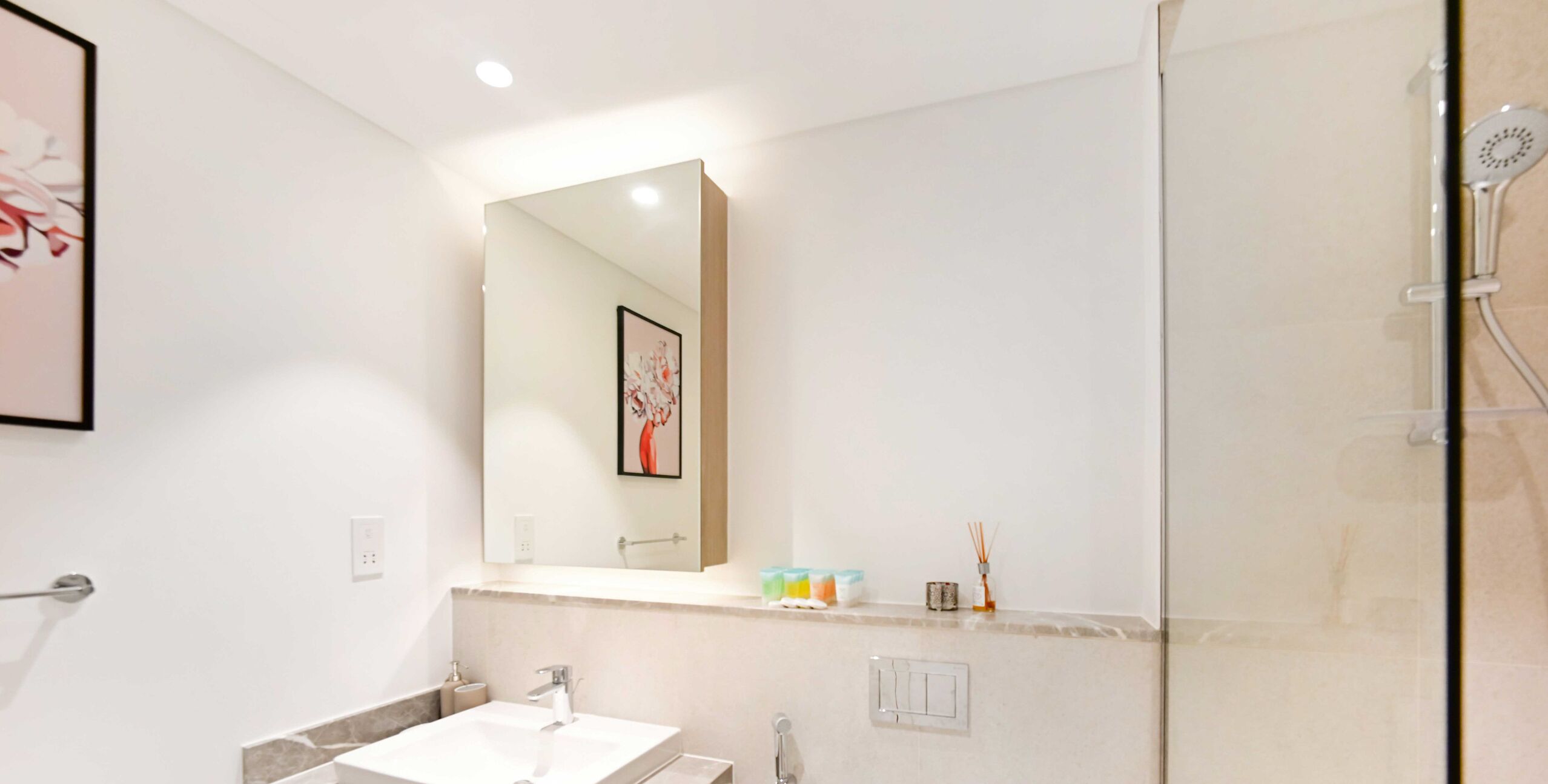 Une salle de bain moderne avec un grand miroir, un lavabo et une douche.