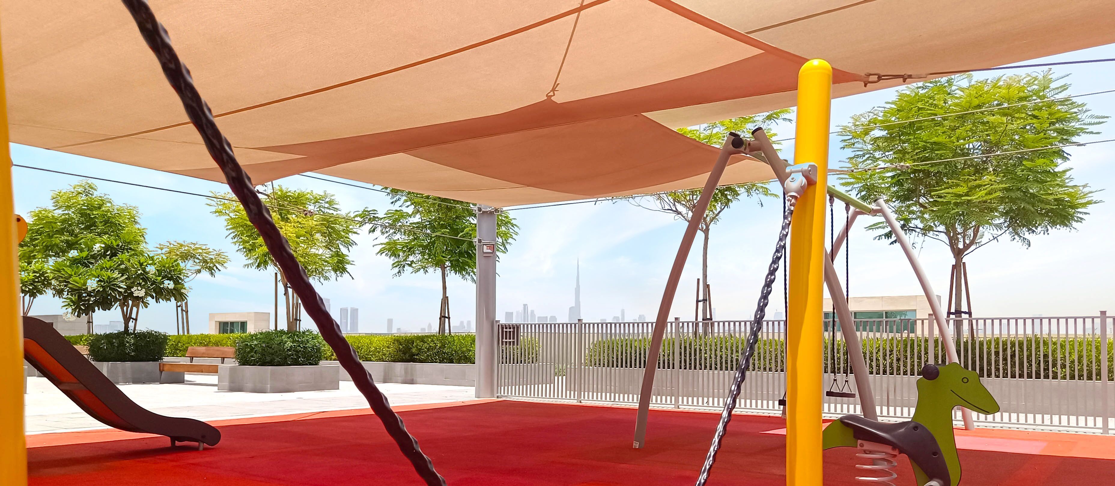A playground with a red carpet, swings, and a climbing structure.