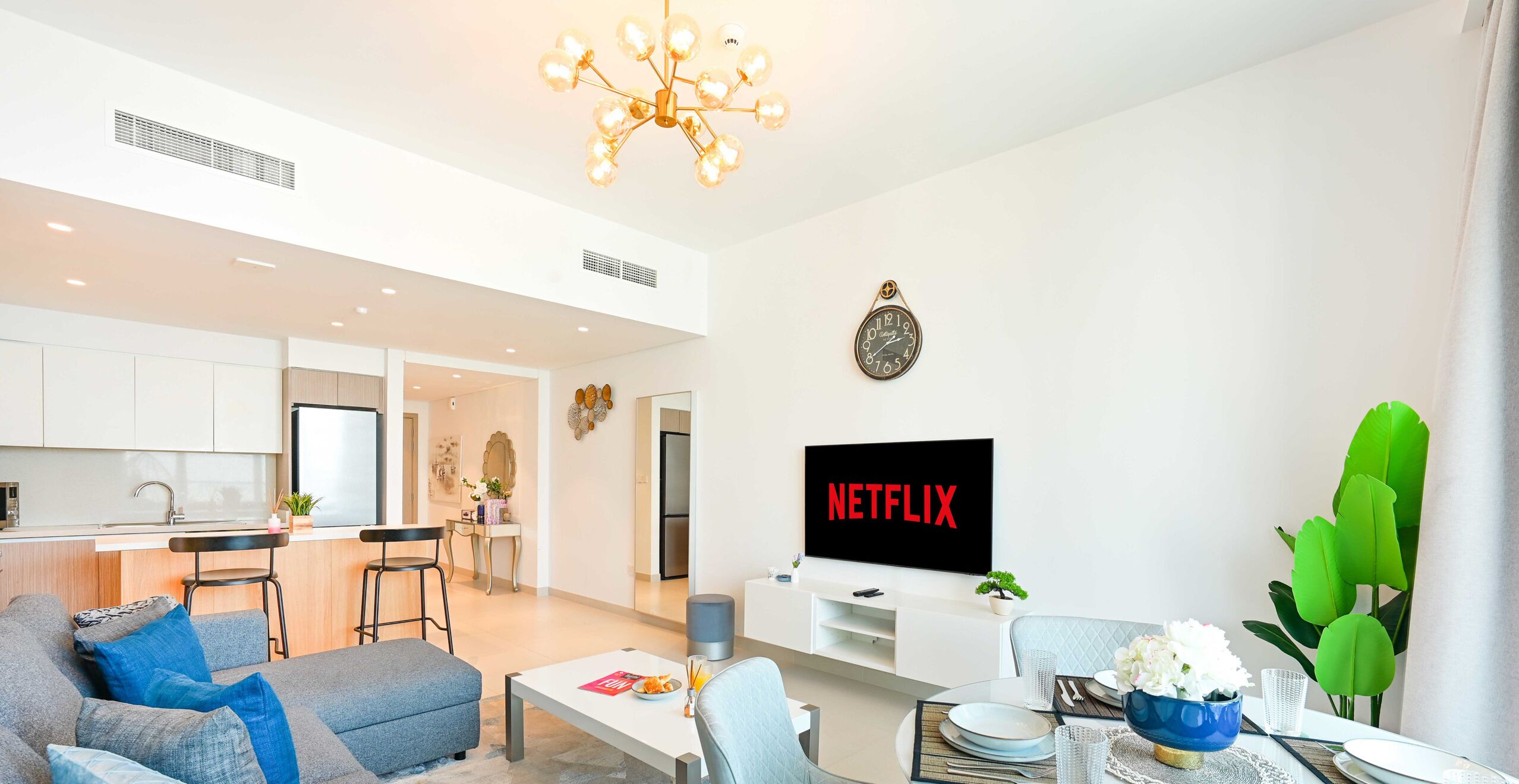 A modern living room with a sofa, coffee table, and a TV displaying "NETFLIX".