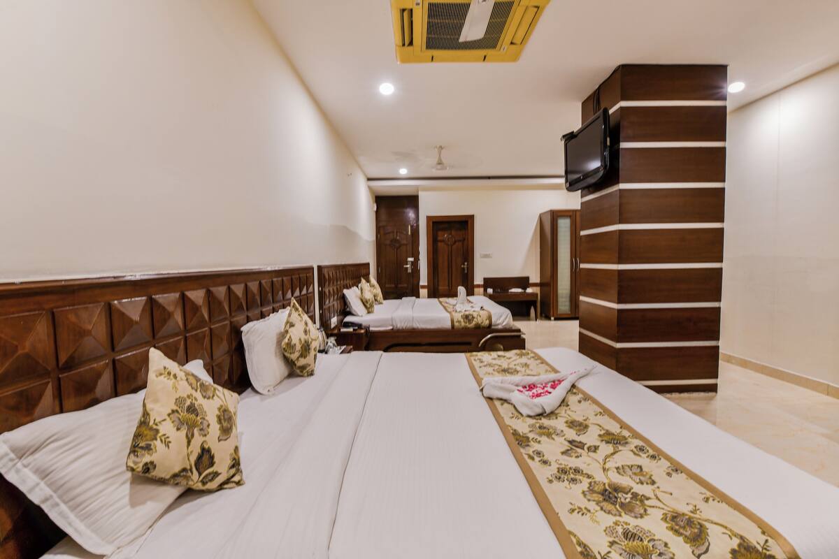 A hotel room with two beds, a TV, and a wooden headboard.