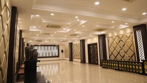Un hall d’entrée spacieux, doté d’un sol poli, de panneaux muraux décoratifs et d’un éclairage encastré.