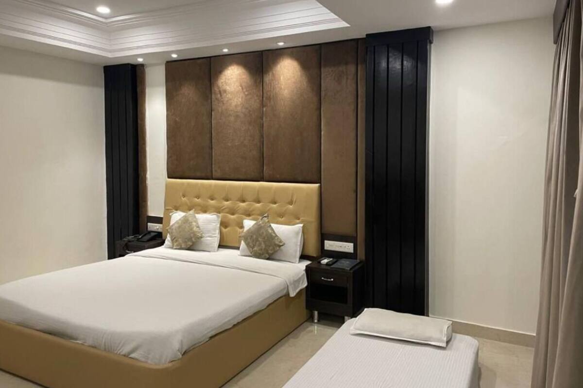 A modern bedroom with a large bed, a headboard with vertical panels, a bedside table with a lamp, and a nightstand.