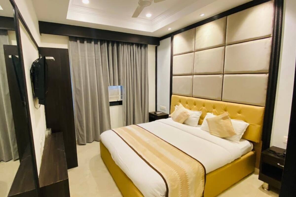A modern hotel room with a large bed, a television, and a desk.