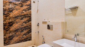 Une salle de bain moderne avec un mur en marbre, un lavabo blanc et une douche.