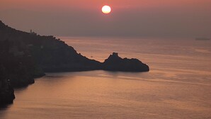 Un atardecer sobre un paisaje costero con acantilados rocosos y aguas tranquilas.