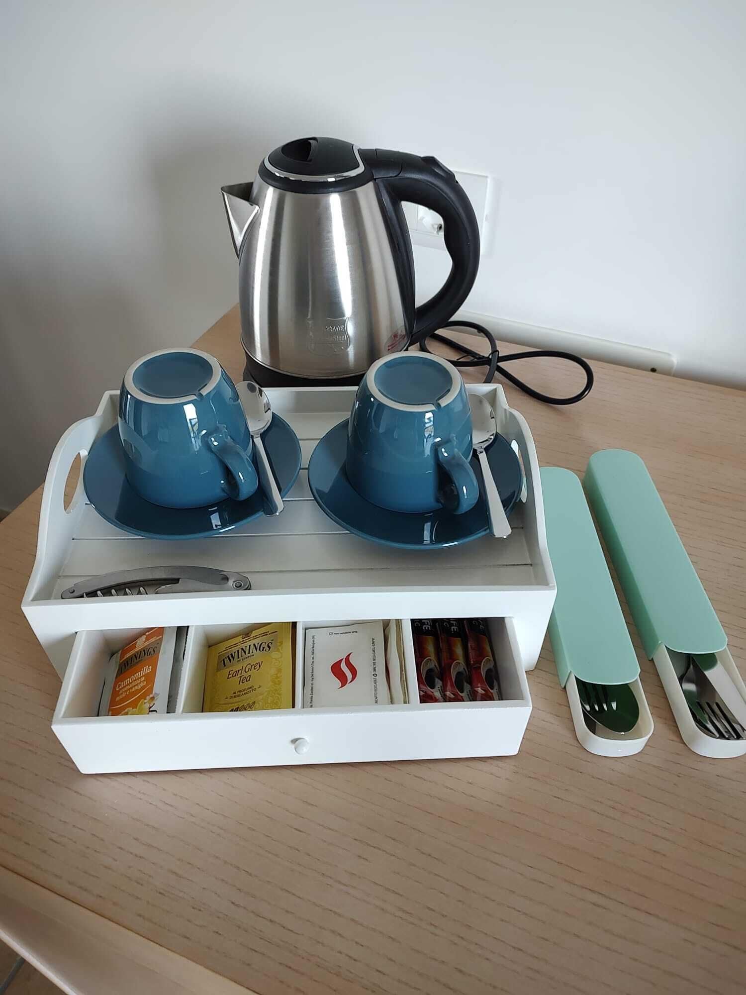A tea set with a kettle, cups, and utensils on a tray.