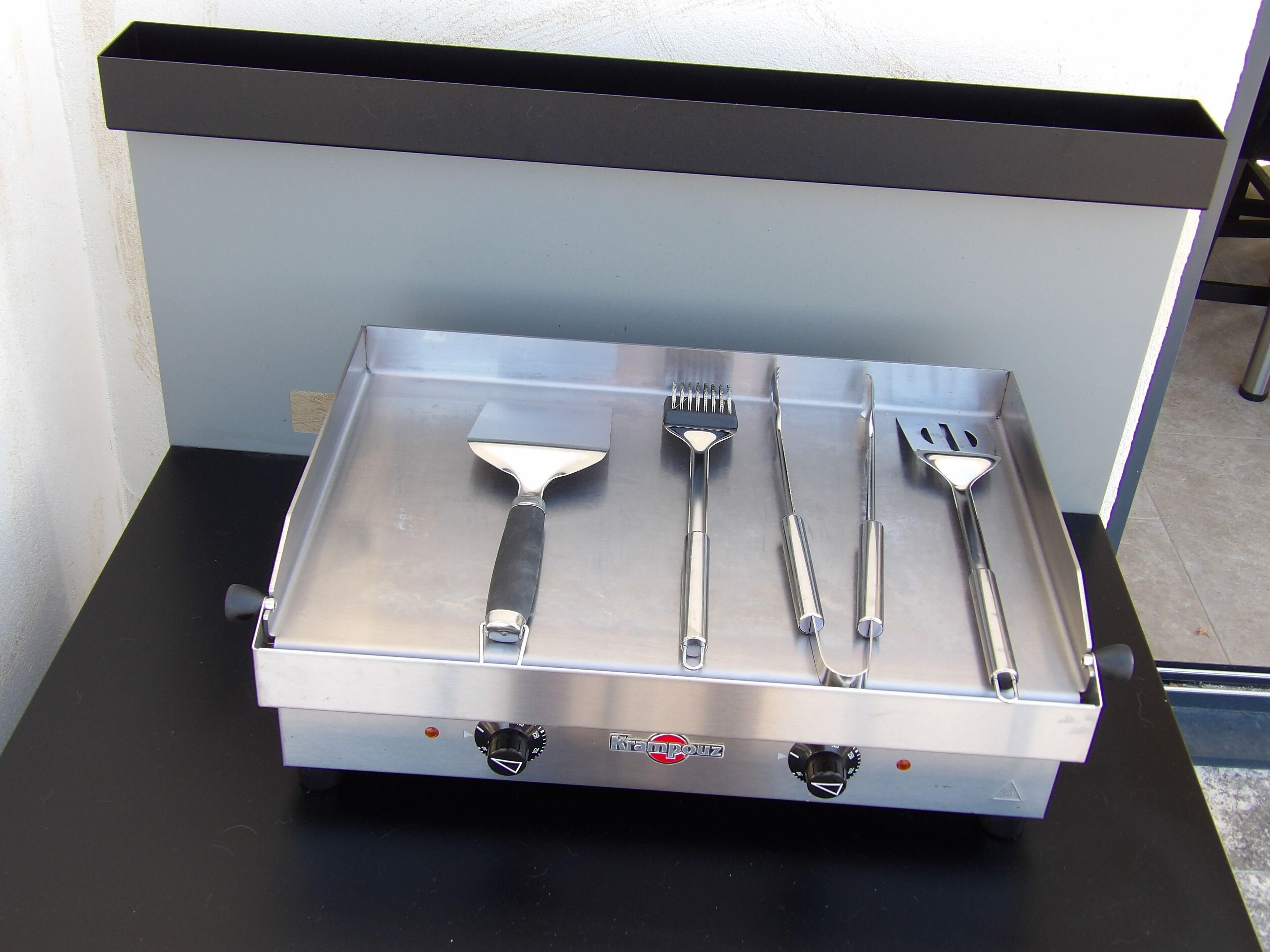 Cocina de acero inoxidable con una bandeja que contiene diversos utensilios.