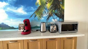 A kitchen counter with a red electric kettle, a silver toaster, and a silver microwave.
