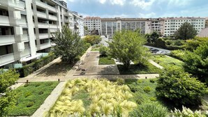 A residential building with multiple balconies and a landscaped courtyard with benches and trees.