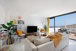 A modern living room with a sofa, television, and dining area.