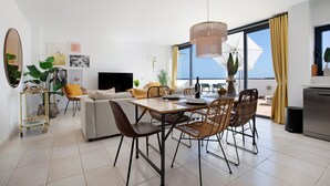 A modern living room with a sofa, dining table, chairs, and a TV.