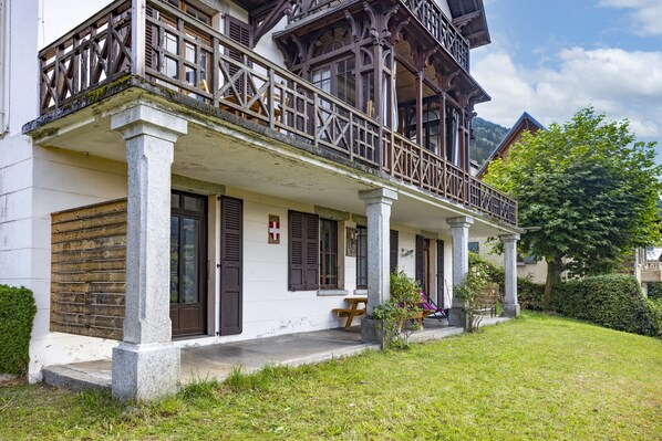 A traditional building with a balcony, stone columns, and a wooden door.