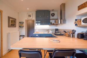 A modern kitchen with a central island, stainless steel appliances, and a dining area with chairs.