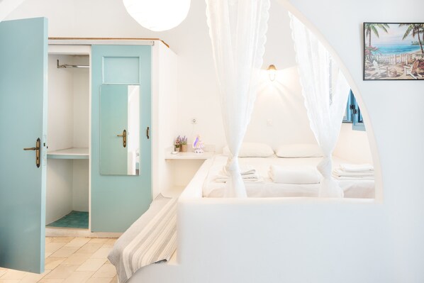 A bedroom with a bed, a wardrobe, a mirror, and a bedside table.