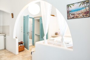 Une chambre avec un lit, une salle de bain avec une douche et un coin repas avec une table et des chaises.