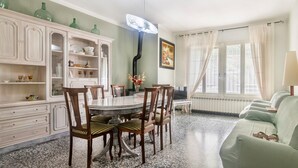 A dining area with a round table, chairs, a cabinet with dishes, and a green sofa. - Holiday Home 'Cal Marcos' with Private Terrace, Private Garden and Wi-Fi (Torregrossa)