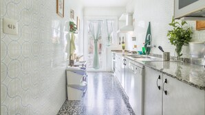 A kitchen with white tiled walls, a granite countertop, and a door leading to a balcony. - Holiday Home 'Cal Marcos' with Private Terrace, Private Garden and Wi-Fi (Torregrossa)