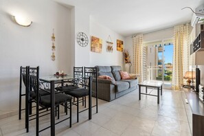 A living room with a sofa, dining table, chairs, and artwork on the walls.