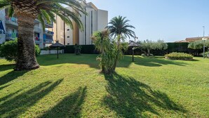 Un patio con palmeras, un paraguas de paja y un edificio con balcones.