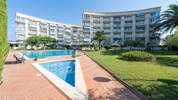 Un hotel con piscina, varios balcones y un césped bien cuidado.
