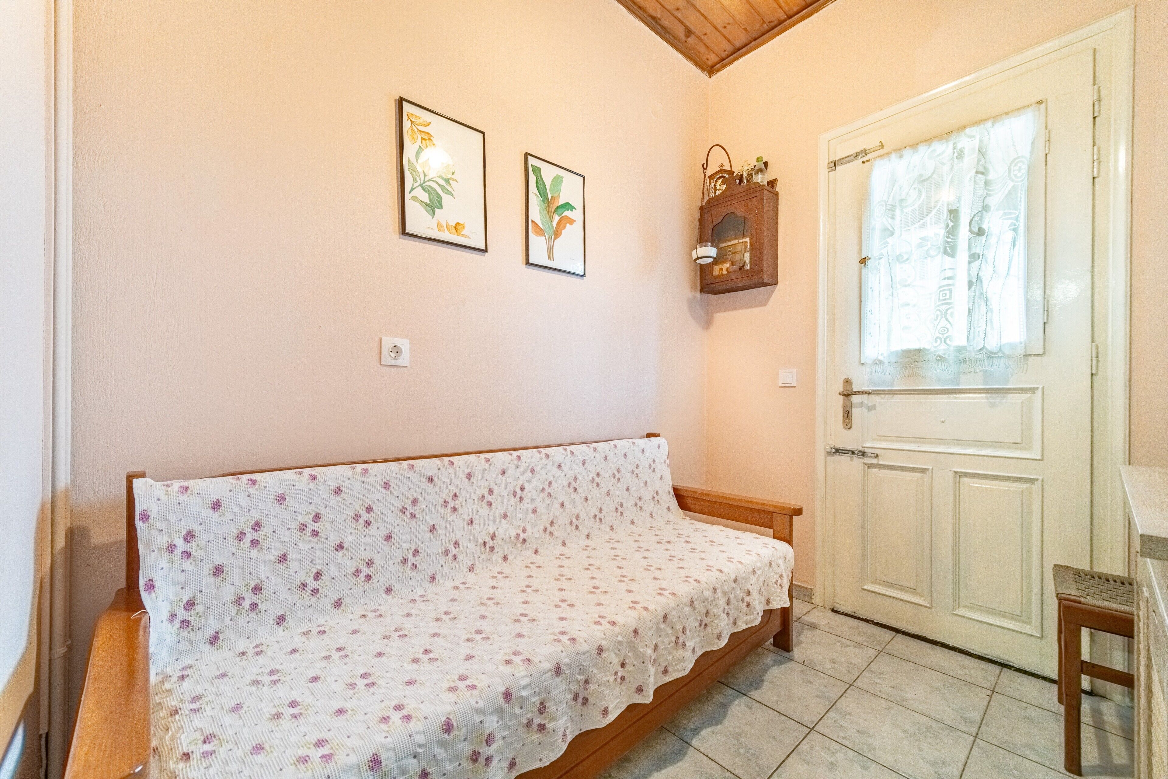 A room with a sofa, a door with a window, and two framed pictures on the wall.