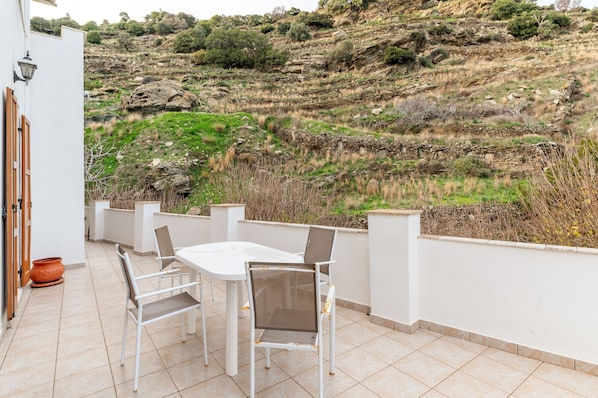 A terrace with a table and chairs, overlooking a rocky hillside.