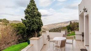 Une terrasse avec une table et des chaises, une lampe et une vue sur les collines.