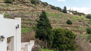 Une colline avec un bâtiment blanc, un grand arbre et un paysage rocheux.