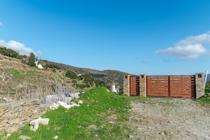 A rural landscape with a stone wall, a grassy hill, and a wooden gate.