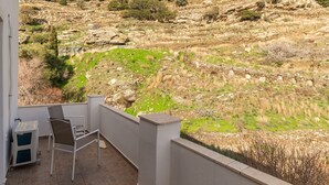 Ein Balkon mit Blick auf einen felsigen Hügel, ein Stuhl und ein kleiner Tisch.