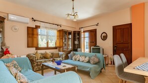 Ein Wohnzimmer mit zwei Sofas, einem Couchtisch, einem Fernseher und einem Esstisch mit Stühlen.