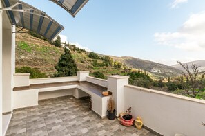 Terraza en la azotea con vista a un paisaje montañoso, una planta en maceta y una maceta roja.