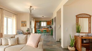 Un salon avec un canapé, un coin repas avec des chaises, une cuisine à l’arrière-plan et un grand miroir sur le côté droit.
