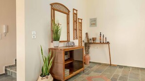 Un couloir avec une console en bois, un miroir, une plante en pot et une étagère décorative.