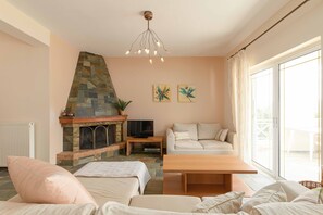 A living room with a stone fireplace, a sofa, a coffee table, and a television.