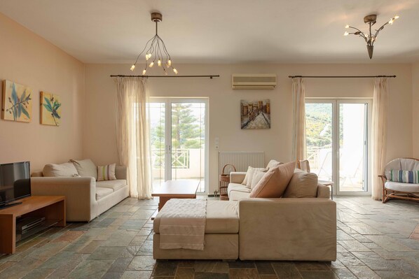 A living room with a sofa, a TV, a table, and a chandelier.