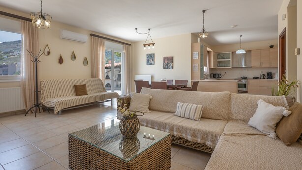 A living room with a sofa, a glass coffee table, and a kitchen in the background. - Holiday Home 'Villa Melenia 1' with Private Pool, 5 Minutes from the Beach, Wi-Fi & Air Conditioning (??. ?e?a??a)