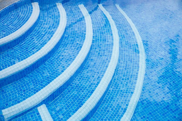 Une piscine avec un bord carrelé et un design incurvé.