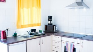 Una cocina moderna con armarios blancos, microondas, cafetera y estufa.