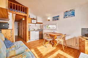 A cozy room with a bed, a dining table with chairs, a kitchen area, and a window. - Apartment 'Appartement Avec Balcon St Honore' (Saint-Honoré)