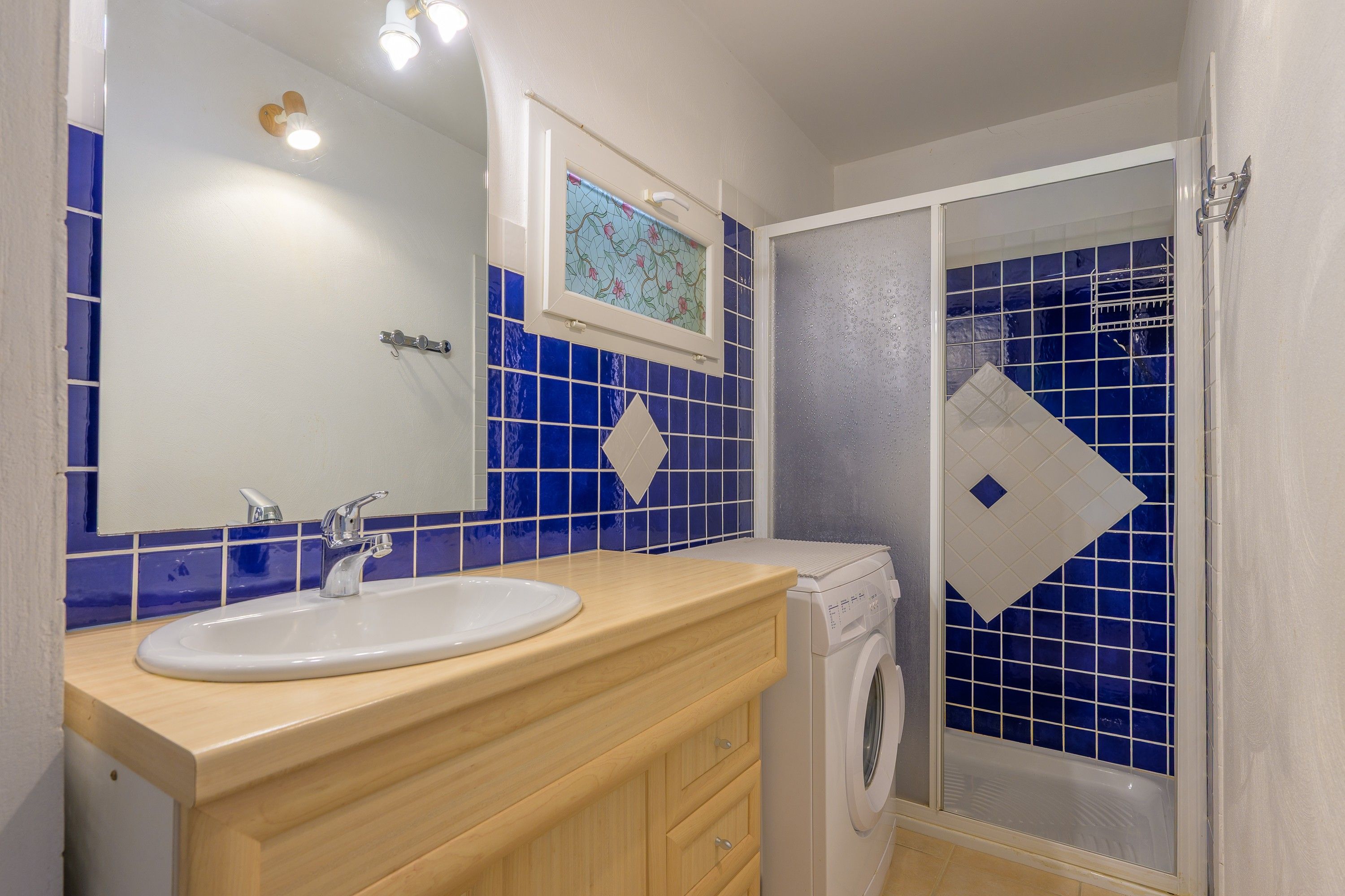 Een badkamer met een wastafel, spiegel en douche met glazen deur.