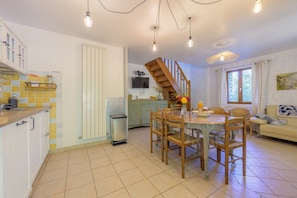 Una cocina amplia con comedor, una escalera y una sala de estar con sofá y ventana.