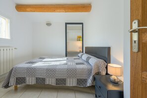 A bedroom with a bed, a dresser, a mirror, and a window.
