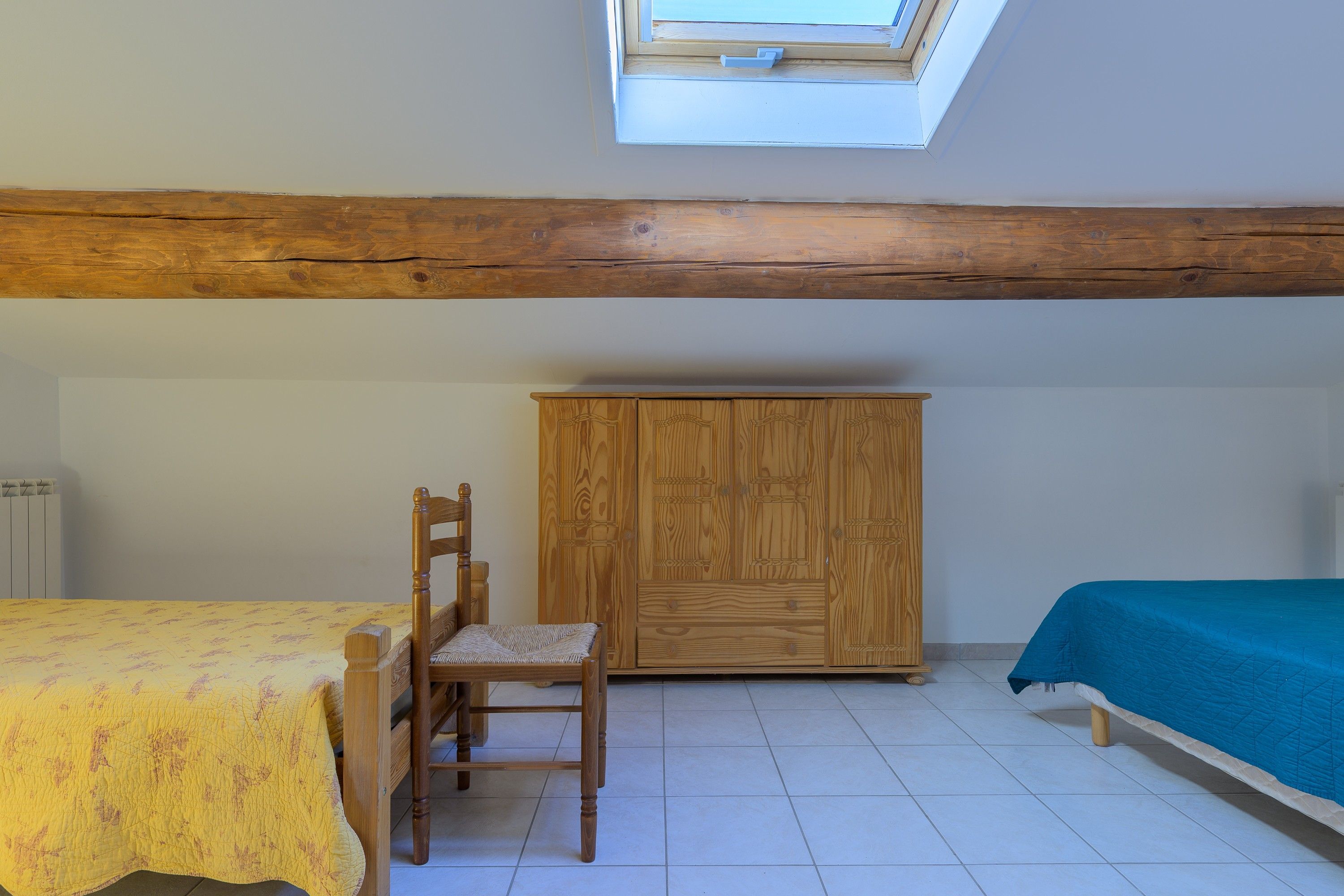 Een kamer met een bed, een stoel, een kledingkast en een dakraam.