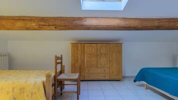 Een kamer met een bed, een stoel, een kledingkast en een dakraam.