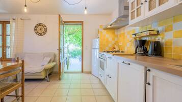 A kitchen with a dining area, a clock on the wall, and a view through an open door.