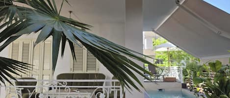 Ett takförsett utomhusområde med en pool, vit räcke och planterade växter i krukor.